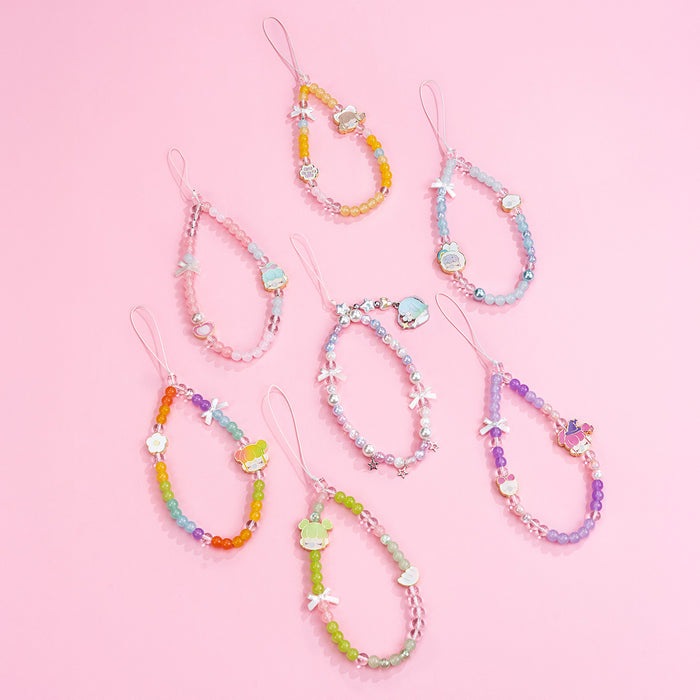 Seven Rolife Nanci Sweet Time beaded phone lanyards in rainbow, blue, pink, green, purple and pearl colors laid out on a pink surface.