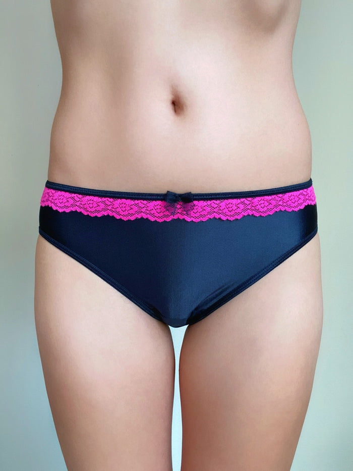 Hot pink lace-trim waistband on dark panties, front close-up on torso.
