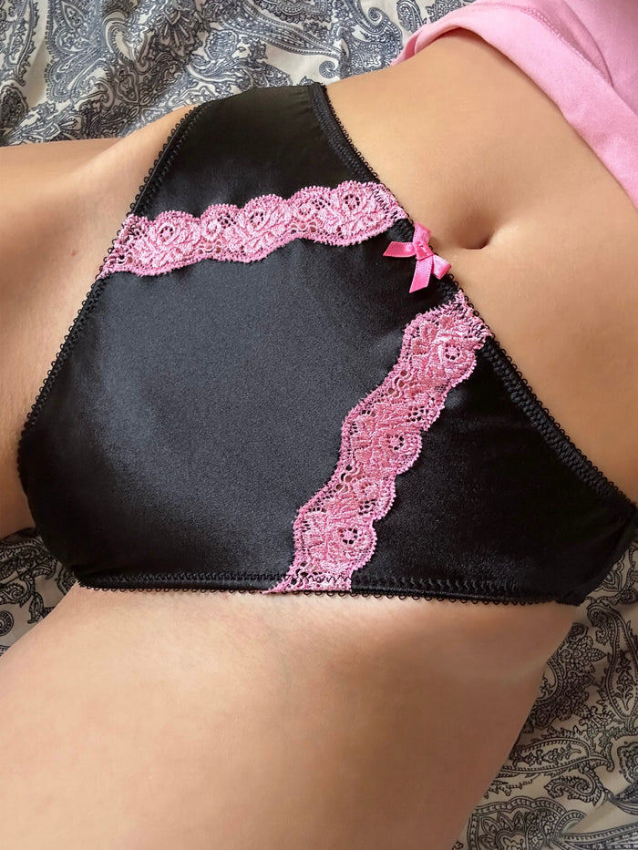 Black satin panty with bubblegum pink lace trim and bow accents at center