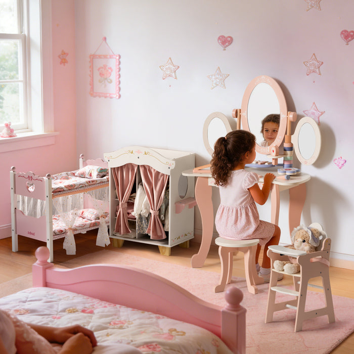 Young girl seated at a ROBUD triple-mirror vanity playing makeup in a pink room with doll bunk bed and wardrobe nearby.