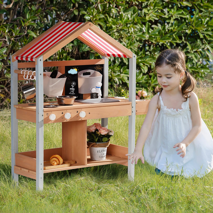 Girl in white dress playing beside ROBUD outdoor mud kitchen with canopy while another girl reaches up to the roof panel outdoors