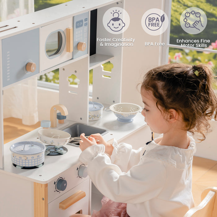 Young girl reaches across a white ROBUD wooden play kitchen with microwave, oven, and sink, BPA-free badge visible.