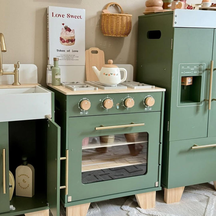 Close-up of ROBUD vintage green play oven with copper knobs and open door beside the refrigerator in a softly styled playroom