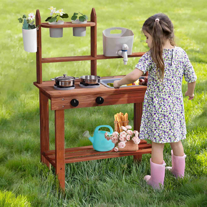 Young girl in floral dress watering herbs beside a ROBUD brown outdoor wooden mud kitchen on green grass