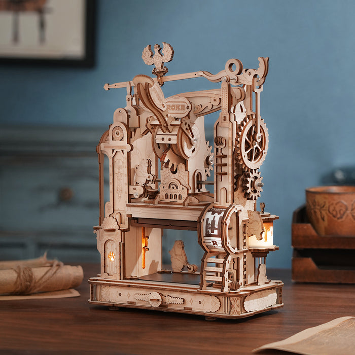 ROKR Classic Printing Press assembled wooden model with glowing candle lamp displayed on blue-toned desk