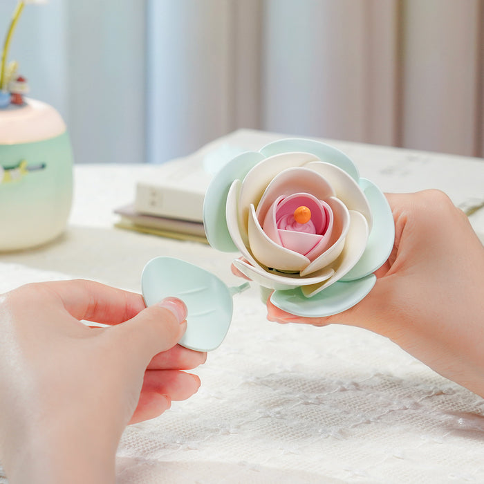 Hands assembling ROKR Minty Camellia Lamp AF02S green camellia blossom with leaf petal piece on a desk beside the completed green lamp