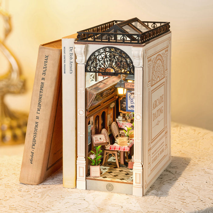 Rolife Arcade Dating Book Nook standing upright between books on a wooden shelf with warm interior LED lighting