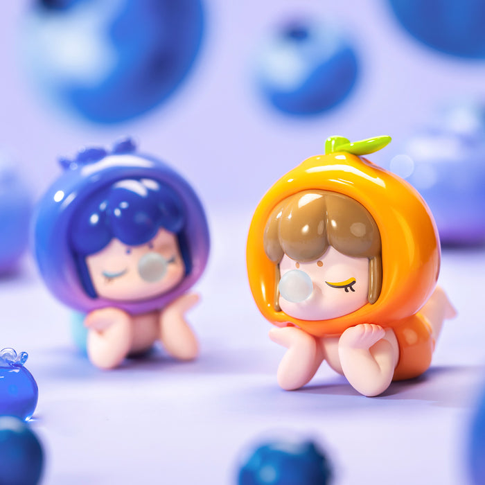 Rolife Baby Nanci Fruits blueberry and orange costume dolls posed together on a soft lavender surface surrounded by scattered blue blueberry props in a lifestyle scene