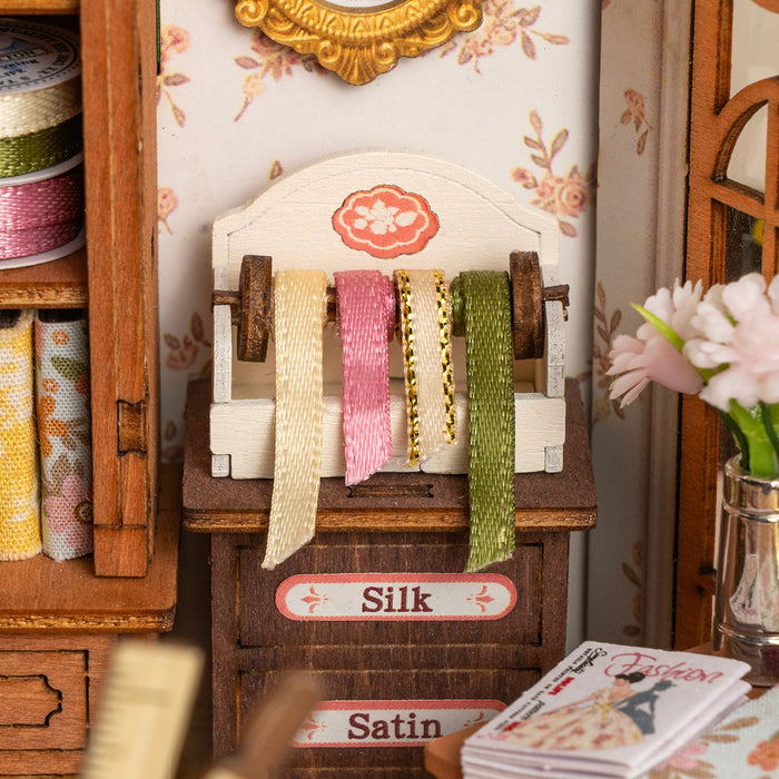 Rolife Elsa's Tailoring DG178 close-up of the miniature wooden ribbon rack holding yellow, pink and green silk ribbons labeled Silk and Satin