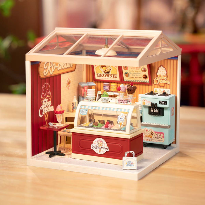 Rolife Flavorful Ice Cream DIY miniature house DW018B lifestyle scene showing the completed red-themed ice cream shop with Ro-cream branding, brownie menu board, and soft warm ambient lighting.