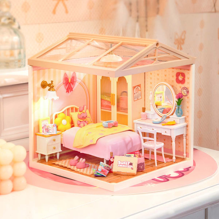 Rolife Lovely Pink Bedroom DIY miniature house DW016 lifestyle scene showing the complete pink bedroom with arched wardrobe, pastel bedding, dressing table, and warm ambient lighting.