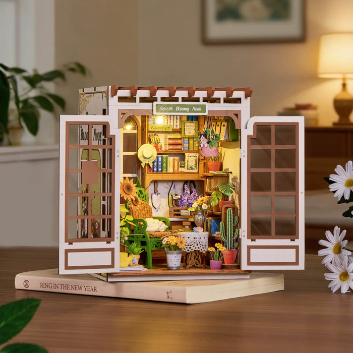 Rolife Secret Bloomy Nook book nook on a wooden desk, warm LED light glowing inside the miniature flower garden scene
