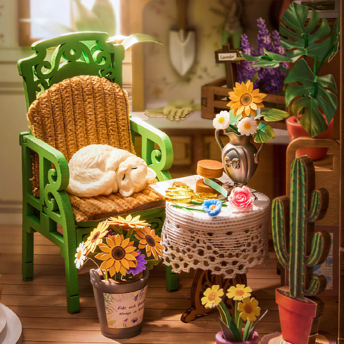 Secret Bloomy Nook interior detail with a green wicker chair, sleeping white cat, sunflowers, and a cactus in terracotta pots