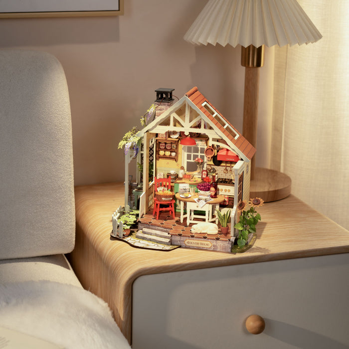 Rolife miniature farmhouse dollhouse placed on a bedside table beside a glowing lamp in a softly lit bedroom