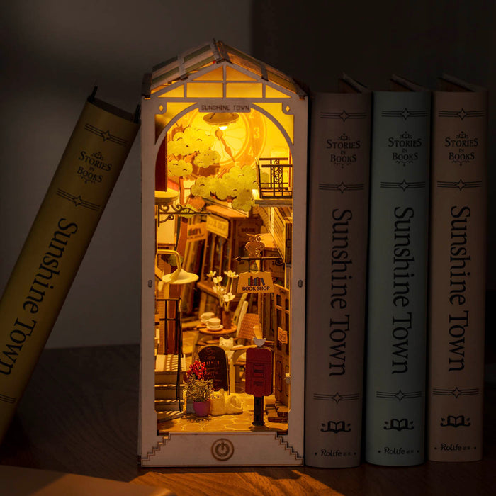 Rolife Sunshine Town book nook tucked between matching hardcover books with warm interior library scene glowing