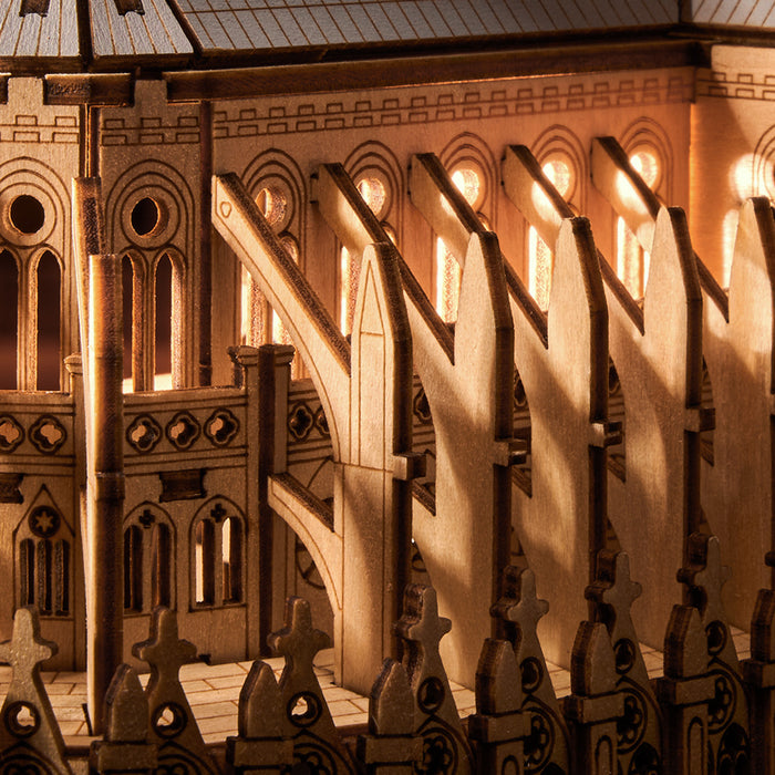 Rowood Paris Cathedral TG511 wooden puzzle photographed from the rear-side showing the apse, flying buttresses, and central spire on a wooden surface with soft background lighting