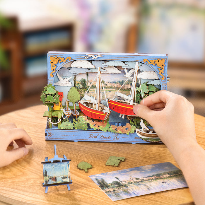 Hand placing a puzzle piece onto the partially assembled Rolife Red Boats 3D art frame on a table