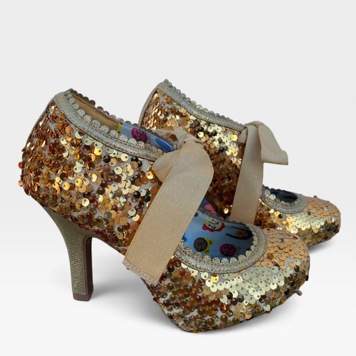Pair of glittery high-heeled shoes with decorative sole on a light gray background