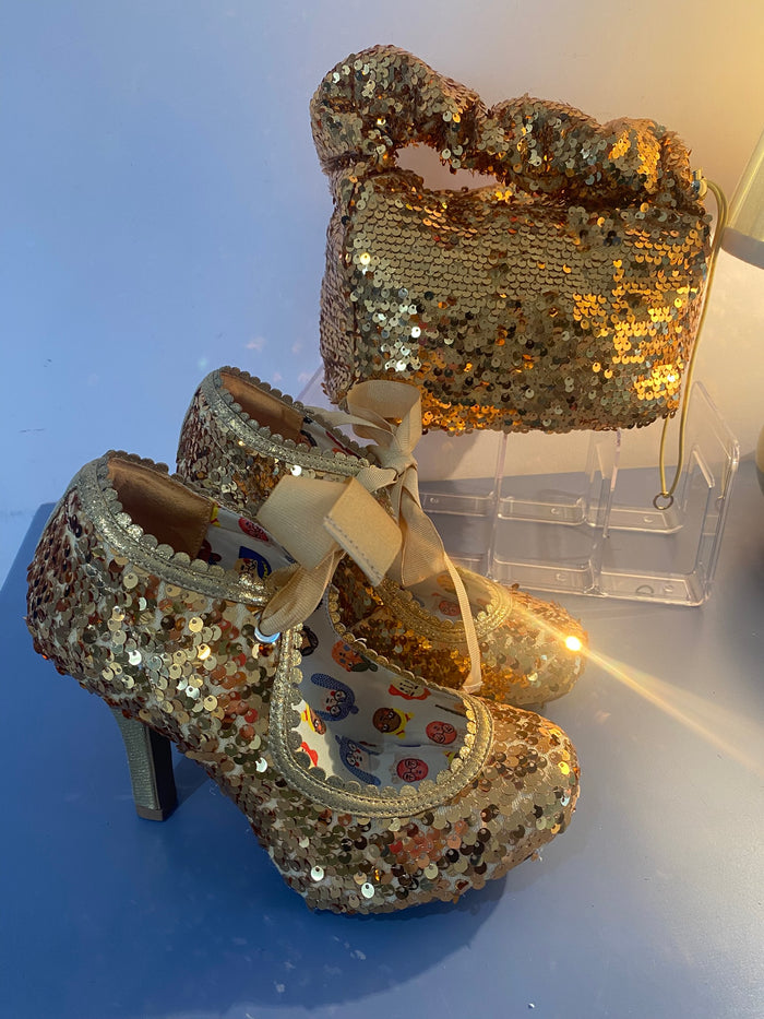 Gold sequin shoes with a matching handbag on a blue background