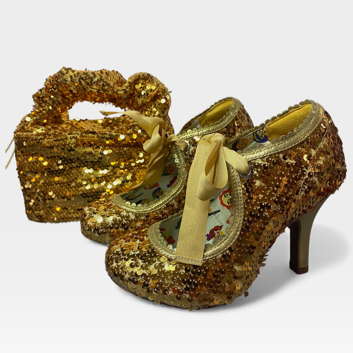 Gold sequin shoes with ribbons on a white background