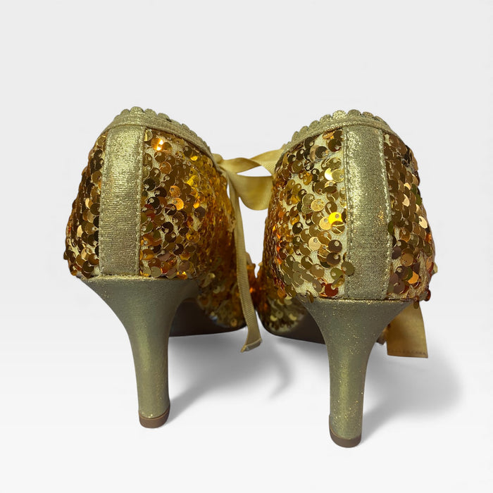 Gold sequin high-heeled shoes on a light gray background